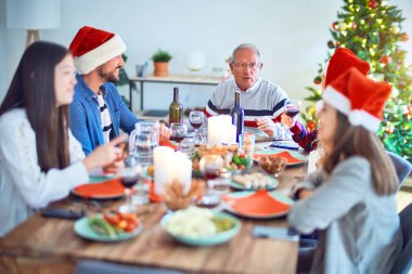 Güzel bir aile Noel Baba şapkası takıyor ve mutlu ve kendinden emin gülümsüyor. Evde kızarmış hindi yiyip Noel 'i kutluyoruz.