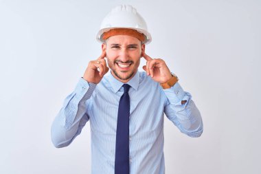 Müteahhit kaskı takan genç bir iş adamı yüksek sesli müzik sesi için kulaklarını parmaklarıyla kapatıyor. Sağır kavramı.