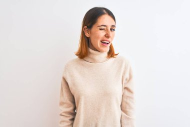 Kış balıkçı yaka kazak giyen güzel bir kadın izole edilmiş arka planda kameraya seksi bir ifadeyle bakıyor, neşeli ve mutlu bir yüzle..