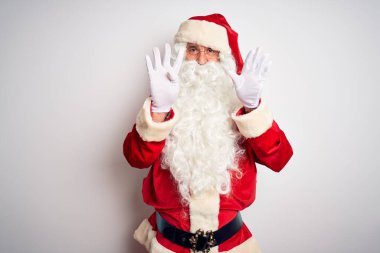 Orta yaşlı, yakışıklı, Noel Baba kostümü giymiş beyaz arka plan üzerinde duran ve dokuz numaralı parmaklarıyla işaret eden kendinden emin ve mutlu bir şekilde gülümseyen adam..