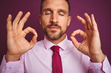 Zarif gömlek giyen ve mor izole edilmiş arka plan üzerine kravat takan iş adamının yakın plan çekiminde rahatlayın ve parmaklarınızla meditasyon hareketi yaparken gözleriniz kapalı gülümseyin. Yoga konsepti.