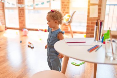 Renkli oyun odasında beyaz güzel bir bebek oyuncaklarla oynuyor. Anaokulunda mutlu ve şen şakrak.