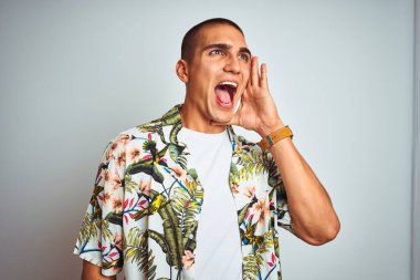 Tatilde beyaz arka planda Hawaii tişörtü giyip el ele tutuşup bağıran yakışıklı bir genç. İletişim konsepti.