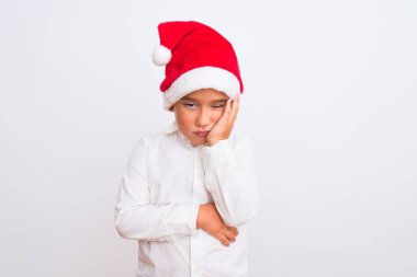 Noel Baba şapkası takan güzel çocuk izole edilmiş beyaz arka plan üzerinde duruyor yorgun ve bunalımda kollarını kavuşturmaktan sıkılmış görünüyor..