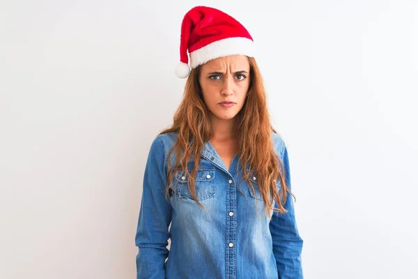 孤立した背景懐疑的で緊張した上でクリスマスの帽子をかぶって若い美しい赤毛の女性は 問題のために動揺して眉をひそめています 負の人 — ストック写真