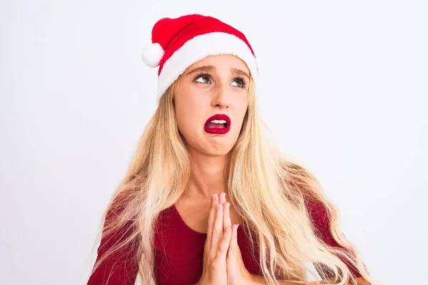 孤立した白い背景物乞いと手で祈る上でクリスマスサンタの帽子を身に着けている若い美しい女性と一緒に顔に希望の表現は非常に感情的で心配しています 許しを求める 宗教概念 — ストック写真