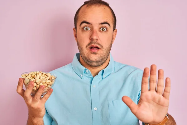 Joven Sosteniendo Tazón Con Pistachos Pie Sobre Fondo Rosa Aislado — Foto de Stock