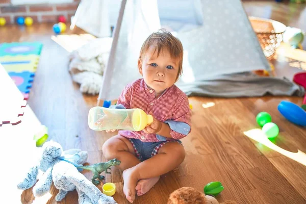 Adorable Niño Pequeño Sosteniendo Biberón Alrededor Muchos Juguetes Jardín Infantes — Foto de Stock