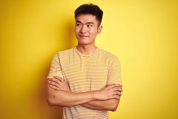 若いですアジアの中国人男性身に着けていますTシャツ上に立って隔離された黄色の背景笑顔側を見て離れて考えて見つめて — ストック写真