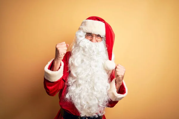 中年英俊男子身穿圣诞老人服装 站在孤立的黄色背景上 非常高兴而兴奋地做着赢家的手势 举起双臂 微笑着 尖叫着要成功 庆祝概念 — 图库照片