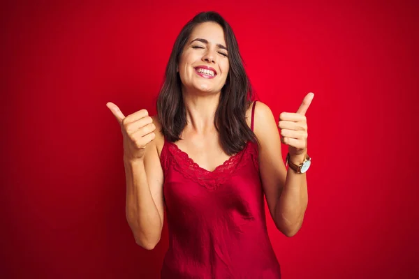 年轻美丽的女人穿着性感的女士内衣 站在红色孤立的背景下 成功地做着积极的手势 微笑着竖起大拇指 快乐着 快乐的表情和胜利的姿态 — 图库照片