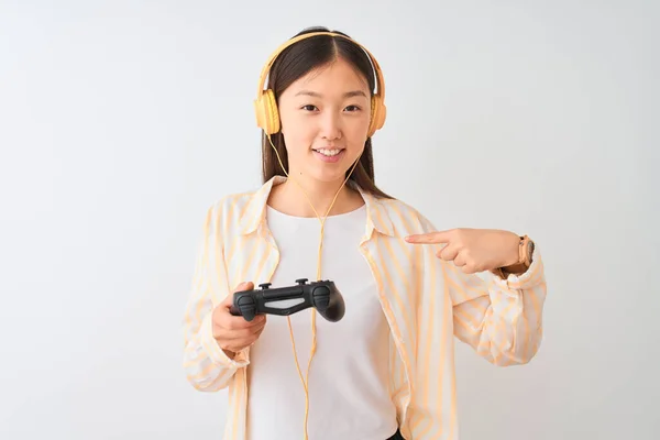 中国玩家妇女玩视频游戏使用耳机在孤立的白色背景与惊喜的脸指向自己 — 图库照片