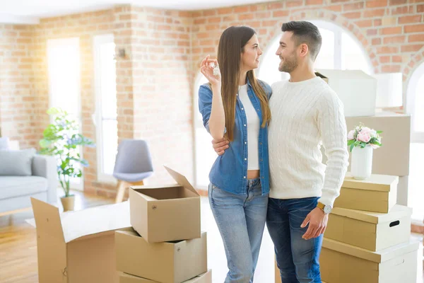 Junges Paar zieht in ein neues Zuhause, umarmt sich verliebt und zeigt Schlüssel — Stockfoto