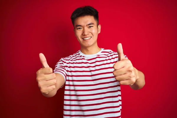 Młody Azjatycki Chińczyk Pasiastej Koszulce Stojący Nad Odizolowanym Czerwonym Tłem — Zdjęcie stockowe