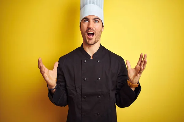 年轻厨师 身穿制服 头戴帽子 站在孤立的黄色背景之上 疯狂而疯狂地大喊大叫 带着咄咄逼人的表情和手臂 沮丧的概念 — 图库照片