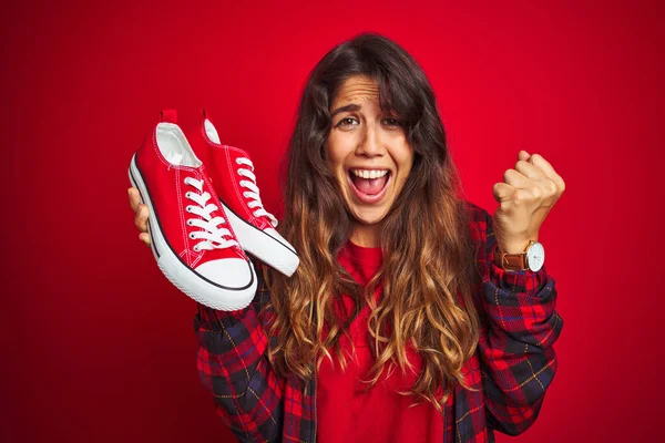 Joven Hermosa Mujer Sosteniendo Zapatillas Pie Sobre Fondo Rojo Aislado —  Fotos de Stock