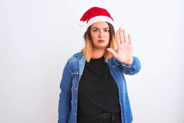 年轻美丽的女人戴着圣诞圣诞圣诞礼帽 站在孤独的白色背景上 手牵着手唱着歌 脸上带有消极而严肃的手势的警告表情 — 图库照片