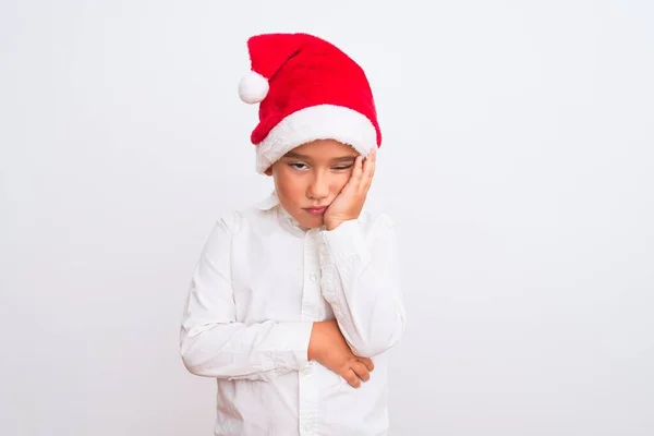 漂亮的小男孩戴着圣诞圣诞圣诞礼帽 站在孤独的白色背景上 满脑子疲惫而厌烦 双臂交叉地陷入忧郁症 — 图库照片