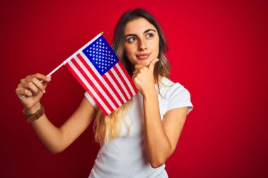 Amerika Birleşik Devletleri bayrağını kırmızı izole edilmiş arka planda tutan genç bir kadın.