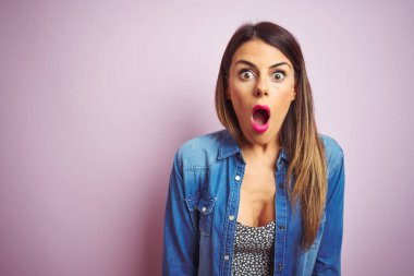 Pembe soyutlanmış arka planda duran genç ve güzel bir kadın. Şaşırmış ve korkmuş bir ifade, korku ve heyecanlı bir yüz..