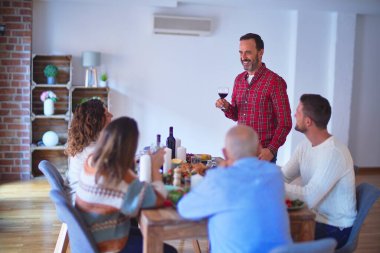 Mutlu ve kendinden emin gülümseyen güzel bir aile. Bir bardak şarapla konuşan adam evde Şükran Günü 'nü kutluyor.