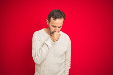 İzole edilmiş kırmızı arka plan üzerinde gri saçlı yakışıklı orta yaşlı bir adam kendini iyi hissetmiyor ve soğuk algınlığı veya bronşitin belirtisi olarak öksürüyor. Sağlık hizmetleri kavramı.