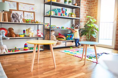 Anaokulundaki raflarda yapı taşlarıyla oynayan güzel bir çocuk.