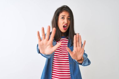 İzole edilmiş beyaz arka plan üzerinde çizgili tişört ve kot giyen genç Çinli kadın avuç içi hareketlerini, kızgın ve hayal kırıklığına uğramış ifadelerini durduruyor.