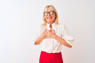 Orta yaşlı iş kadını gömlek ve gözlük takıyor, beyaz arka plan üzerinde duruyor, elleri göğsünde, gözleri kapalı ve yüzünde minnet dolu bir jest ile gülümsüyor. Sağlık kavramı.