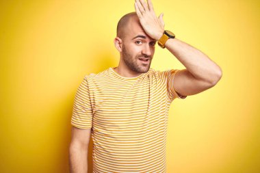 Sarı izole arka plan üzerine sıradan çizgili tişört giyen sakallı genç ve kel bir adam. Hatayla el ele tutuşurken şaşırmış. Hatayı hatırla. Unuttum, kötü hafıza konsepti.