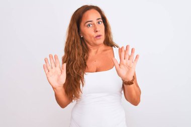 Orta yaşlı olgun bir kadın beyaz arka planda duruyor. Avuçlarını kaldırıyor, reddediyor ve iğrenç bir ifadeyle reddediyor. Dur ve yasakla.