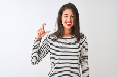 İzole edilmiş beyaz arka plan üzerinde duran çizgili tişört giyen genç ve güzel Çinli kadın gülümsüyor ve el hareketleriyle küçük beden işareti yapıyor ve kameraya bakıyor. Ölçü kavramı.