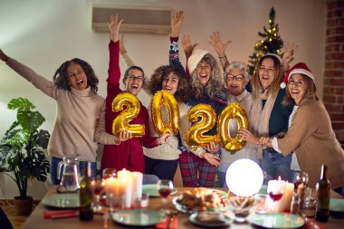 Mutlu ve kendinden emin gülümseyen güzel bir kadın grubu. Evde 2020 balon tutan noel ağacı etrafında poz vermek