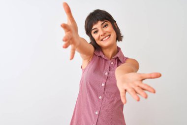 Kırmızı yaz gömleği giyen genç bir kadın izole edilmiş beyaz arka planda durup kameraya bakarak sarılmak için kollarını açmış gülümsüyor. Mutluluğu kucaklayan neşeli bir ifade..