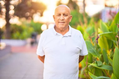 Kıdemli yakışıklı adam mutlu ve kendinden emin gülümsüyor. Kasaba caddesinde yüzünde gülümsemeyle dikilirken