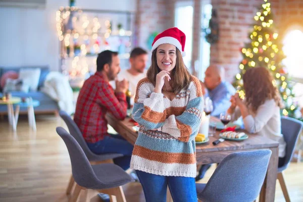 若い美しい女性が幸せと自信を笑顔 家で家族と一緒にクリスマスを祝うサンタの帽子をかぶって — ストック写真