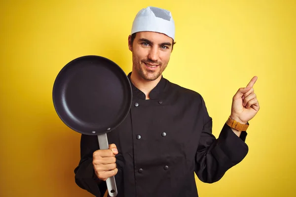 Jonge Chef Kok Uniform Hoed Met Kookpan Geïsoleerde Gele Achtergrond — Stockfoto
