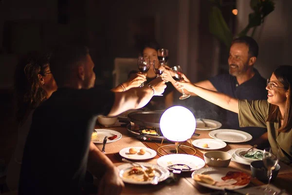 Beautiful family toasting with cup of wine on dinner smiling at terrace