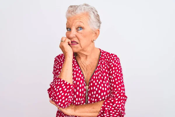 高个子灰发女人穿着红色休闲装 站在孤立的白色背景上 满脸紧张 双手放在咬指甲的嘴上 焦虑问题 — 图库照片