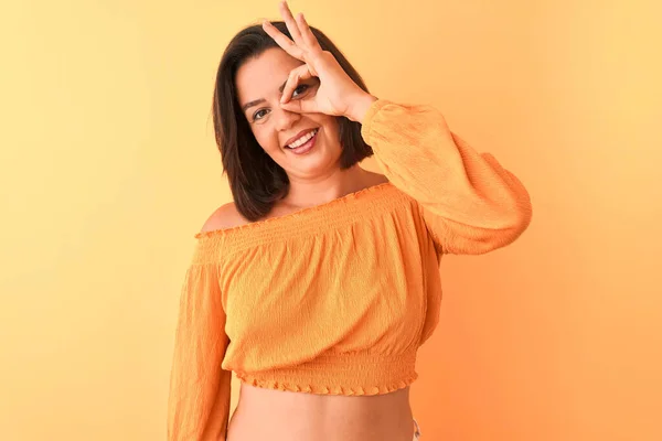 年轻漂亮的女人穿着休闲的T恤 站在孤立的橙色背景上 做着手势 脸上挂着微笑 用手指看着幸福的脸 — 图库照片