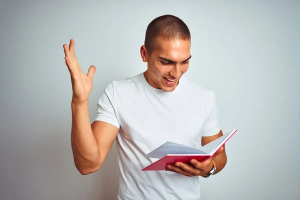Молодой Красивый Мужчина Читает Красную Книгу Белом Изолированном Фоне Счастливый — стоковое фото