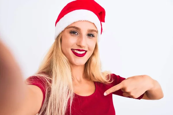 戴着圣诞圣诞圣诞礼帽的女人用相机在孤立的白色背景下自拍 满脸惊讶地指着自己 — 图库照片