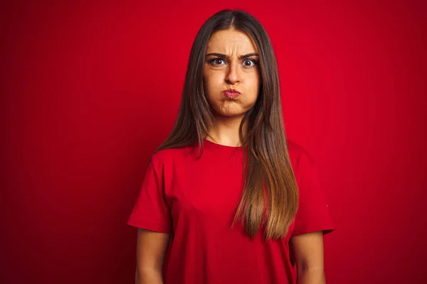 Jovem Mulher Bonita Vestindo Camiseta Sobre Fundo Vermelho Isolado Soprando — Fotografia de Stock