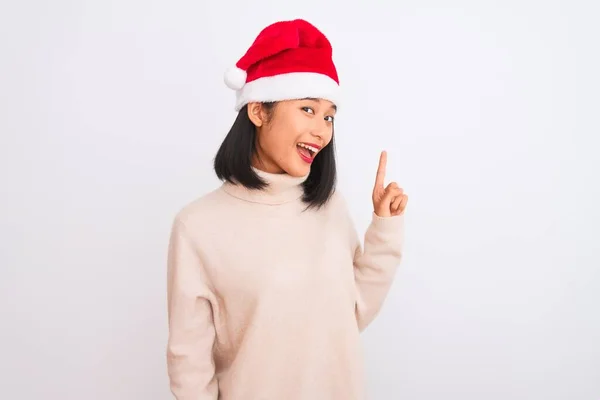 若い美しい中国の女性は 成功したアイデアで指を指す隔離された白い背景の上にクリスマスサンタの帽子を身に着けている 興奮し 第一番 — ストック写真