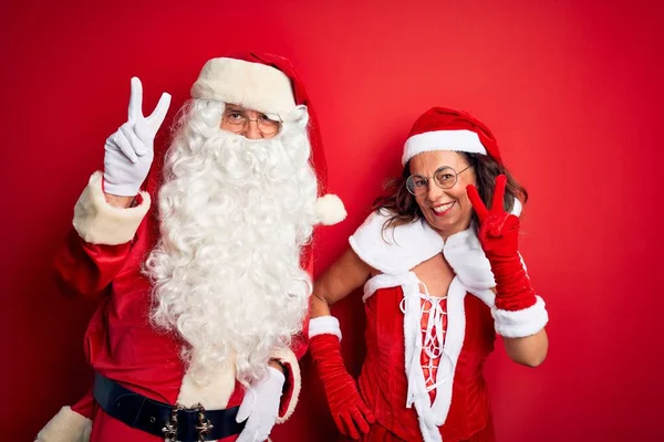 Paar Mittleren Alters Weihnachtsmannkostüm Und Brille Vor Isoliertem Rotem Hintergrund — Stockfoto