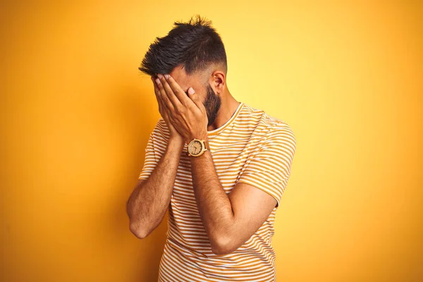 泣きながら手で顔を覆う悲しい表情で孤立した黄色の背景の上に立つTシャツを着た若いインド人男性 うつ病の概念 — ストック写真
