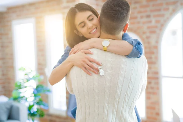 Νεαρό ζευγάρι που μετακομίζει σε ένα νέο σπίτι, αγκαλιάζοντας την αγάπη δείχνοντας τα κλειδιά — Φωτογραφία Αρχείου