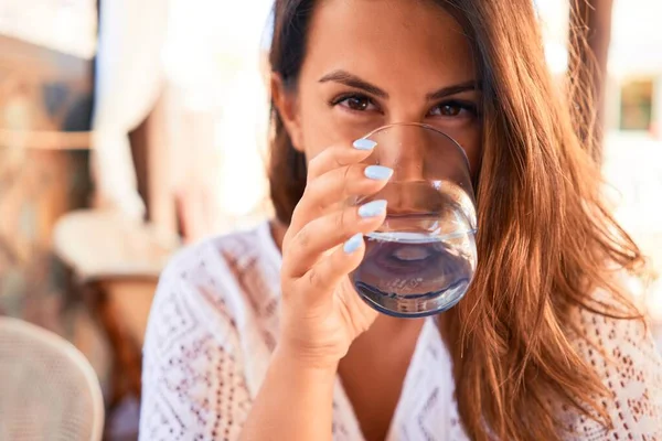 夏休みを楽しむレストランに座っている若い美しい女性水のグラスを飲む — ストック写真