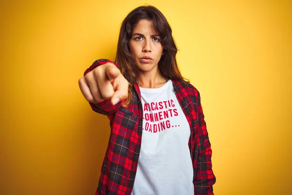 Beautiful woman wearing funny t-shirt with irony comments over isolated yellow background pointing with finger to the camera and to you, hand sign, positive and confident gesture from the front