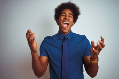 Afro saçlı, mavi gömlekli ve kravatlı Amerikalı iş adamı izole edilmiş beyaz arka planda başarı için çılgın ve çılgın bir kutlama yapıyor kolları havada ve gözleri kapalı heyecanla bağırıyor. Kazanan konsept